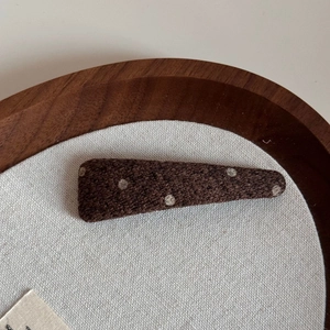Close-up of vintage dark brown polka dot fabric hair clip on a wooden display tray