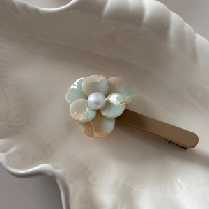 Detailed close-up of marble pattern acetate flower hair clip with pearl center decoration