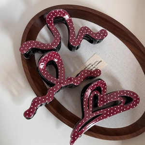 Détail de trois pinces à cheveux rouge foncé à pois et paillettes sur plateau en bois