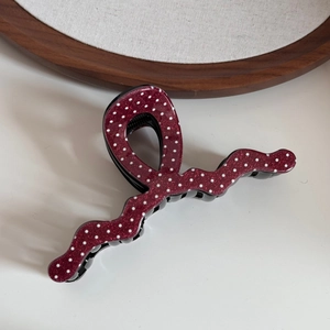 Vue macro d'une pince à cheveux ondulée rouge foncé avec pois blancs et finition pailletée