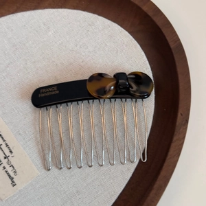 Close-up of tortoise shell bow hair comb with ten metal teeth and handmade engraving