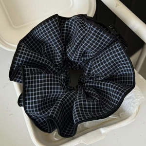 Macro detail of large blue plaid scrunchie showing fine fabric texture and black edge stitching