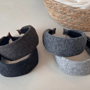 Close-up of four thick knit headbands in grey tones with wool-like textured fabric