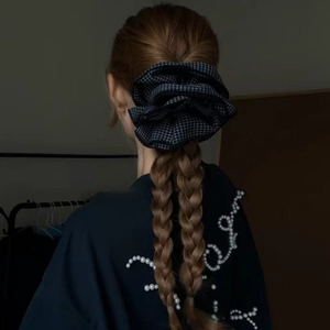 Detail of extra large plaid scrunchie in black and white worn on braided hair