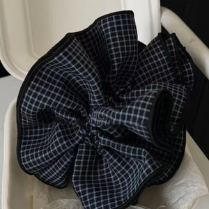 Macro detail of large plaid scrunchie with grey checkered pattern and layered fabric texture