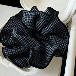 Oversized blue and black plaid check scrunchie with soft ruffled fabric texture