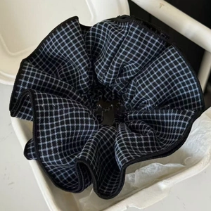 Detailed view of large blue plaid scrunchie with pleated layers in white paper packaging