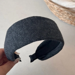 Detail of a thick dark grey knitted headband with soft felt texture and anti-slip lining