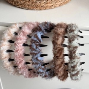 Close-up of five plush headbands with comb teeth in various soft faux fur colors