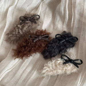 Detailed view of four faux shearling hair clips with PU leather bows in autumn colors