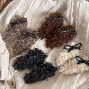 Flat lay of plush lamb wool hair clips with leather bows in four autumn colors