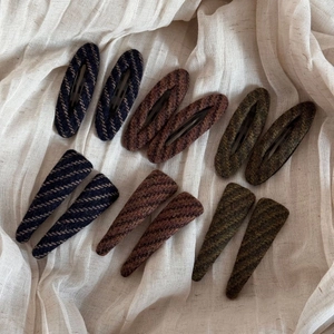 Detailed view of tweed fabric texture on retro striped hair clips in autumn colors