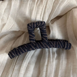 Close-up of vintage navy blue fabric texture and stitching on large hair claw clip