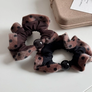 Close-up of plush velvet hair scrunchies with leopard print and pearl bead decoration