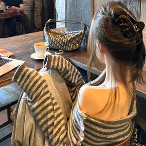 Détail d'une grande pince à cheveux léopard fixant un chignon dans un café chaleureux