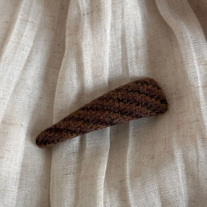 Close-up of brown tweed fabric texture on a large retro hair claw clip for women