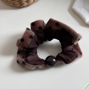 Close-up of brown plush polka dot scrunchie with soft faux fur and black pearl detail