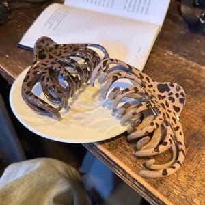 Gros plan de pinces à cheveux à motif léopard marron et beige dans un plateau en céramique