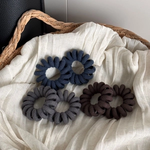 Close-up of spiral phone cord hair ties with twill fabric texture in earthy tones