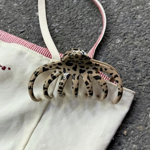 Gros plan d'une pince à cheveux léopard fixée sur un sac en toile blanc robuste