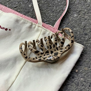 Détail d'une grande pince à cheveux à motif léopard sur un sac en toile blanc cassé