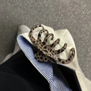 Détail d'une pince à cheveux motif léopard en résine durable sur une toile beige