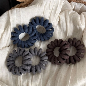 Detailed texture of fabric-covered spiral hair ties in navy blue, grey and brown colors