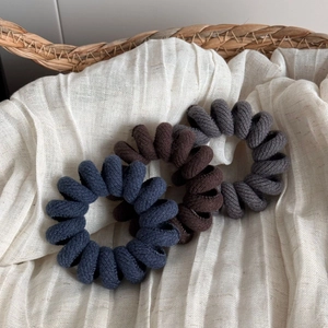 Detailed macro view of spiral fabric telephone wire hair ties in three neutral colors
