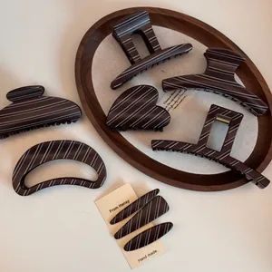 Detail view of large dark brown hair claw clips and matching pins with white stripes