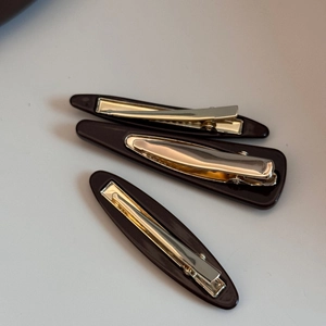 Detail view of coffee brown resin hair clip set with sleek glossy finish and metal springs