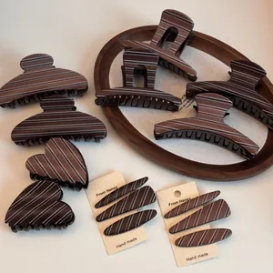 Detailed set of brown striped claw clips and hairpins on a wooden tray for styling