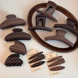 Detail of dark brown resin hair claw clips with white stripes on a wooden tray