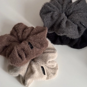 Gros plan de chouchous en peluche oversize aux tons terre avec étiquettes faites main