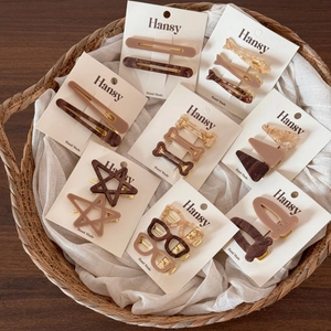 Various acetate hair clips with star and sunglasses shapes on a display card