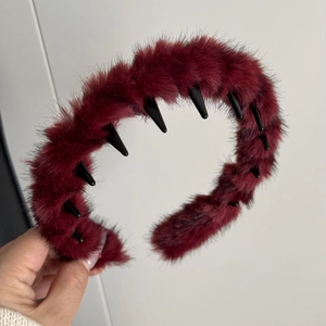 Détail de la texture en peluche rouge vin et des dents en plastique noir du serre-tête