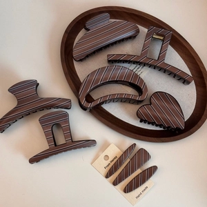 Detail view of large brown hair claws with white stripe patterns on an oval wood tray