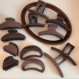 Detailed close-up of brown striped hair claws in heart and geometric shapes on a tray