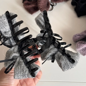 Detailansicht der grauen Strickstruktur und des schwarzen Bandes auf der Haarspange