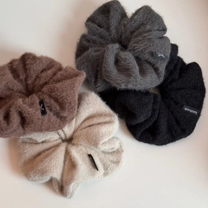 Gros plan de grands chouchous en peluche gris et beige avec étiquette fait main