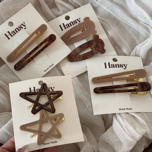 Detail of star and bear shaped acetate hair clips on display card with marble texture