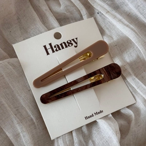 Close-up of matte brown and amber acetate hair clips on display card with metal detail