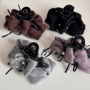 Detailansicht von vier gestrickten Schleifen-Haarklammern mit Perlen in verschiedenen Farben