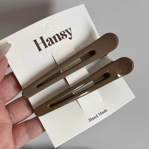 Gros plan de deux pinces à cheveux marron mat sur carte de présentation pour la coiffure