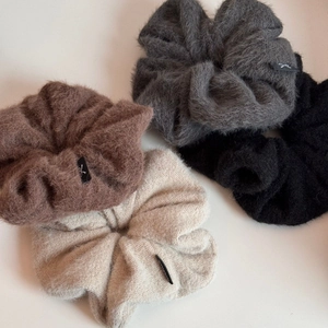 Détail de quatre grands chouchous en peluche en marron, gris, noir et beige avec étiquettes