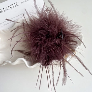 Pince à cheveux en plumes bordeaux avec chaîne de perles sur plat en céramique