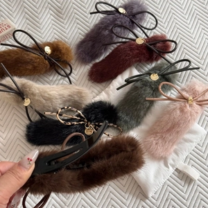 Close-up of plush bow hair clips in multiple colors with golden metal branding tags