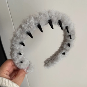 Vue détaillée du serre-tête en peluche grise avec peigne à dents pour coiffure fixée