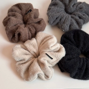 Gros plan de quatre chouchous en peluche en marron, gris, beige et noir à texture tricotée