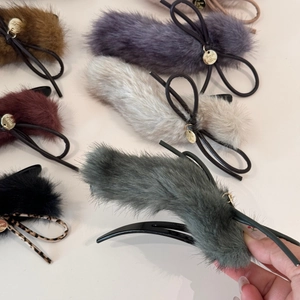 Macro detail of plush hair clips in multiple colors with gold metal tag and fur texture