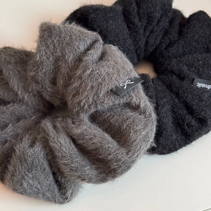 Détail de chouchous en peluche noirs et gris avec étiquettes tissées et texture douce
